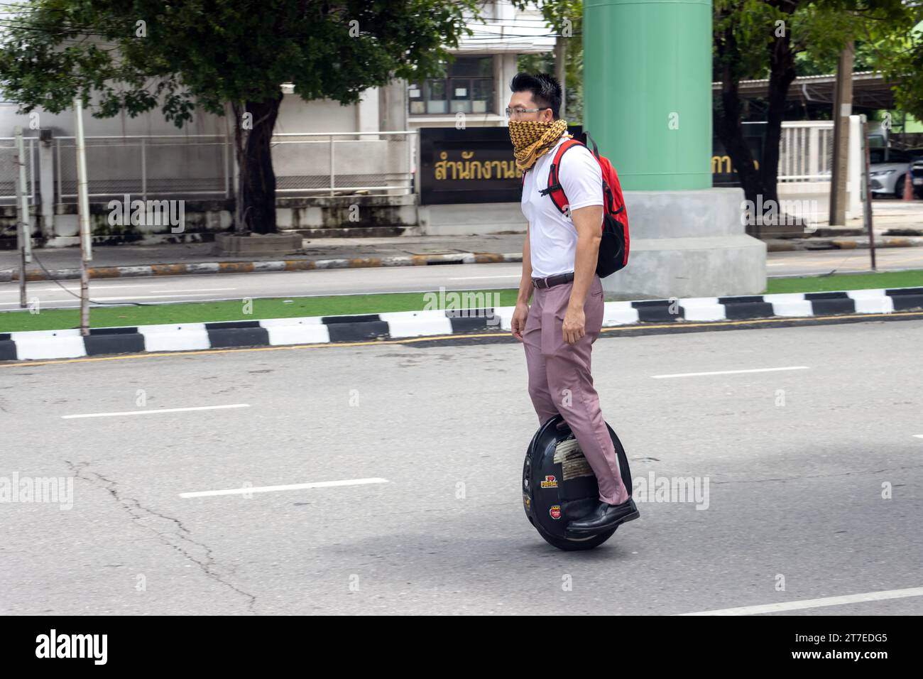 SAMUT PRAKAN, THAÏLANDE, octobre 11 2023, Un homme monte une roue électrique sur une route multiligne dans la ville Banque D'Images