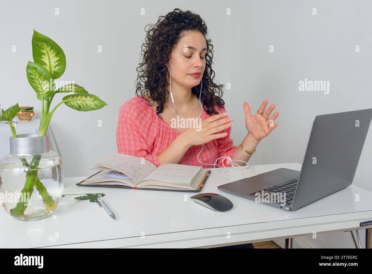 jeune femme d'affaires latine assise dans son bureau parlant sur appel en ligne avec son ordinateur portable à l'aide d'écouteurs et faisant des gestes de la main, affaires et techno Banque D'Images