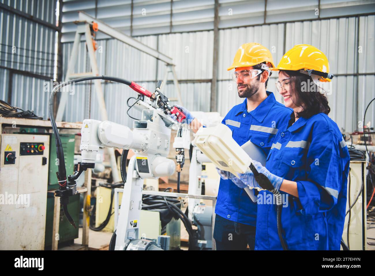 Mécanicien d'équipe d'ingénieurs utilisant le bras robotique de contrôleur d'ordinateur pour souder l'acier dans l'atelier d'usine d'acier. Logiciel de programmation robot industriel pour aut Banque D'Images