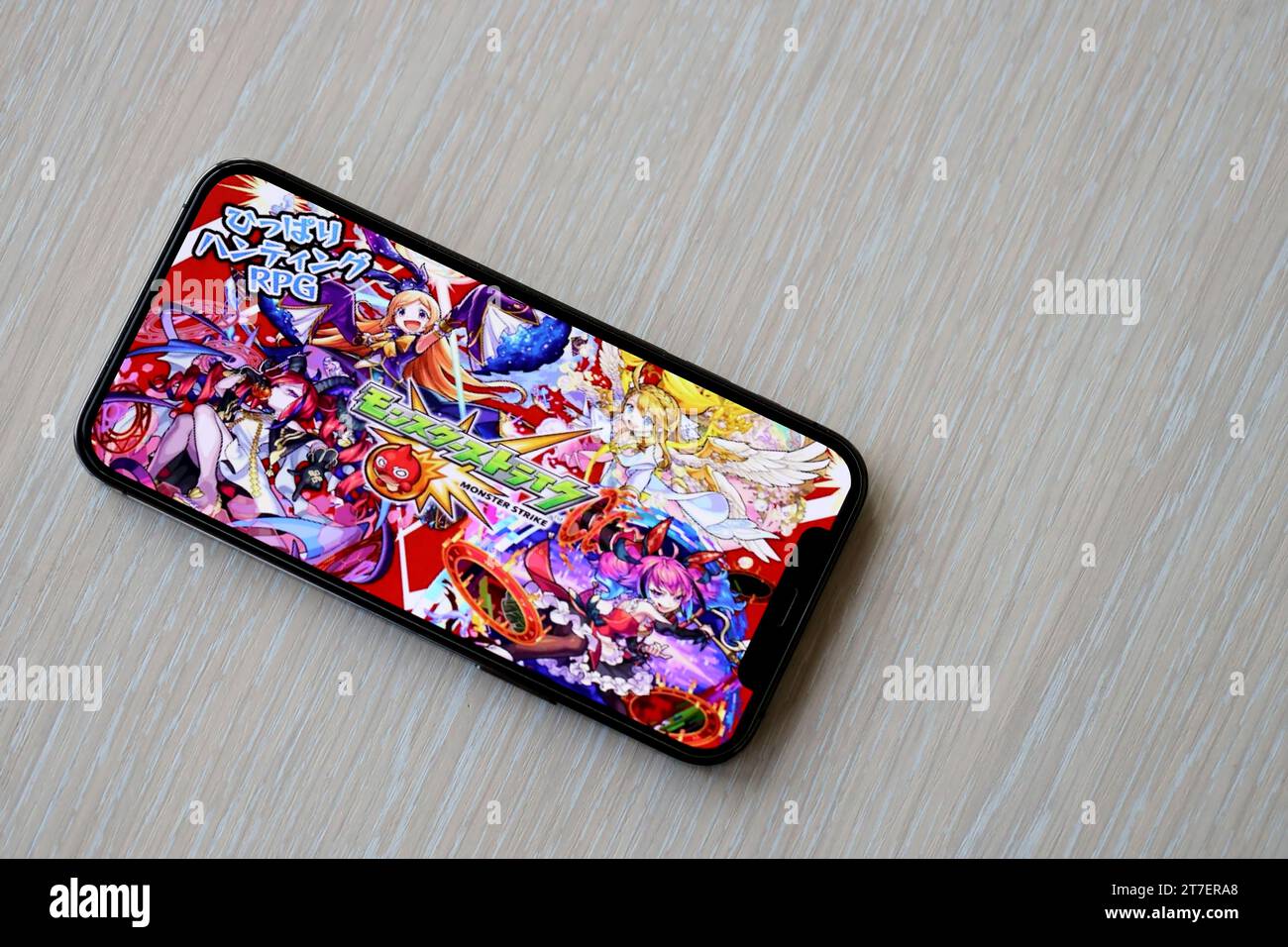 Monster Strike mobile iOS jeu sur iPhone 15 écran de smartphone sur la table en bois pendant le jeu mobile. Jeux et divertissements mobiles sur un appareil portable Banque D'Images