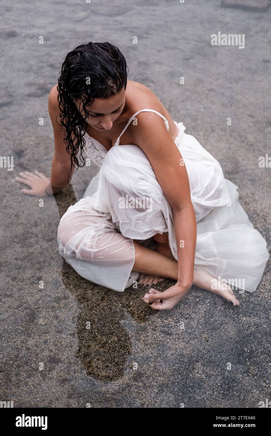 Une femme brune en costume blanc profite d'un moment de détente en profitant des thérapies à l'eau de mer Banque D'Images