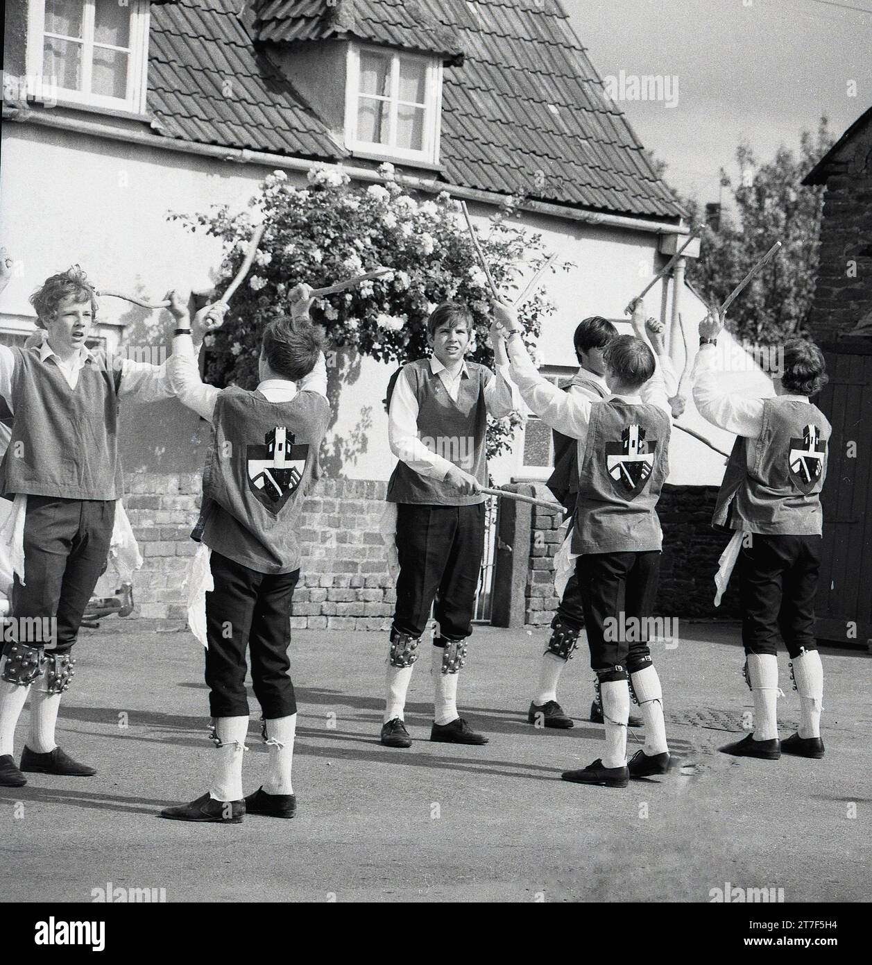 Années 1960, historiques, hommes adultes et jeunes hommes vêtus de costumes faisant une danse morris, Angleterre, Royaume-Uni. La danse Morris est une forme populaire de danse folklorique anglaise jouée lors de festivals et de vacances pour célébrer l'arrivée de l'été et la récolte d'or de l'automne. Banque D'Images