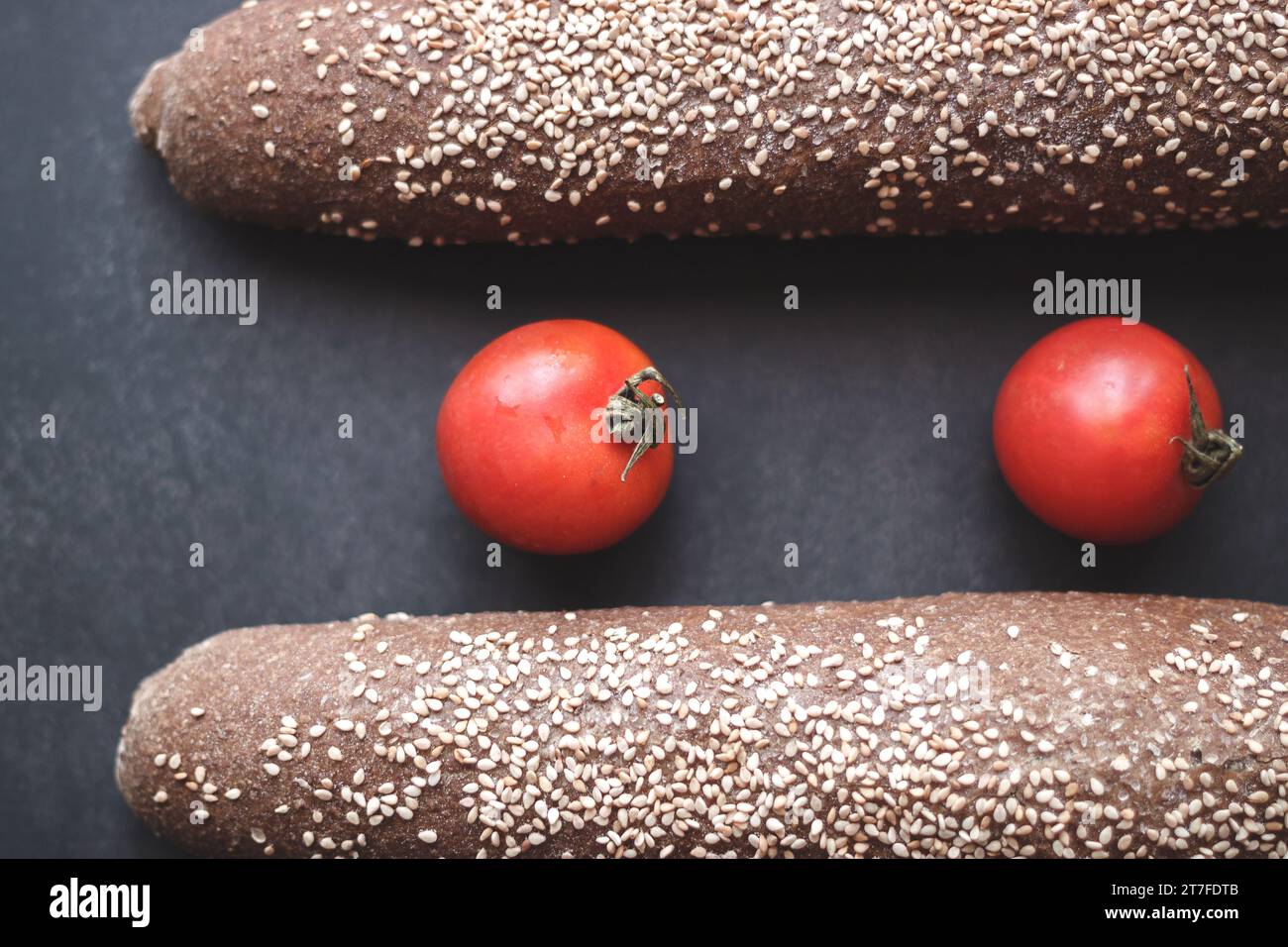 Pain intégral avec deux tomates sur fond noir Banque D'Images