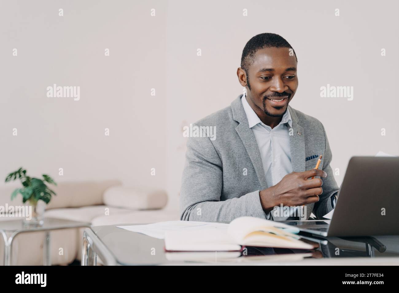 Professionnel Noir homme travaillant à l'ordinateur portable dans le bureau, concentré et souriant Banque D'Images
