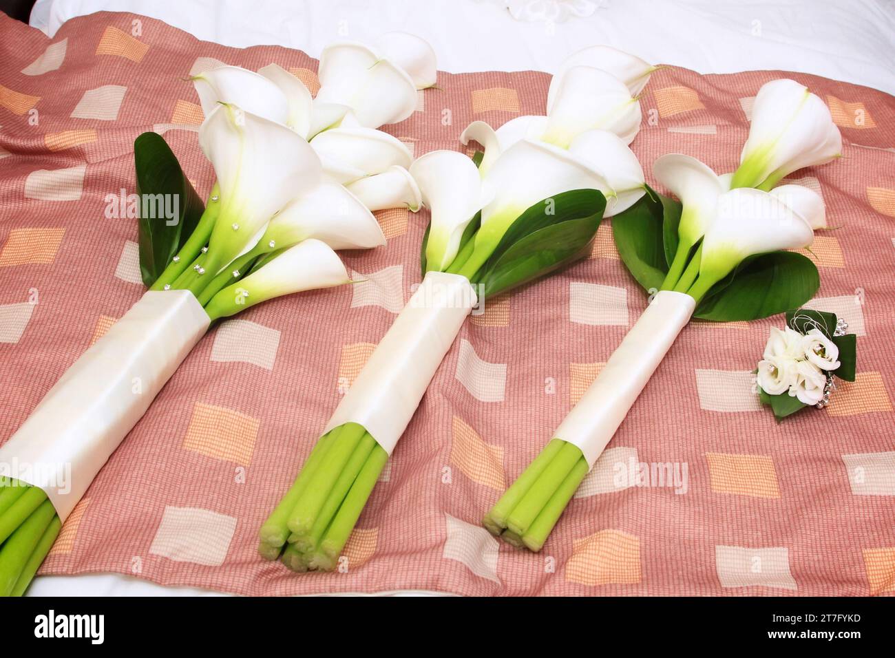 trois bouquets d'orchidées pour un mariage assis dans une rangée et placé sur le lit Banque D'Images