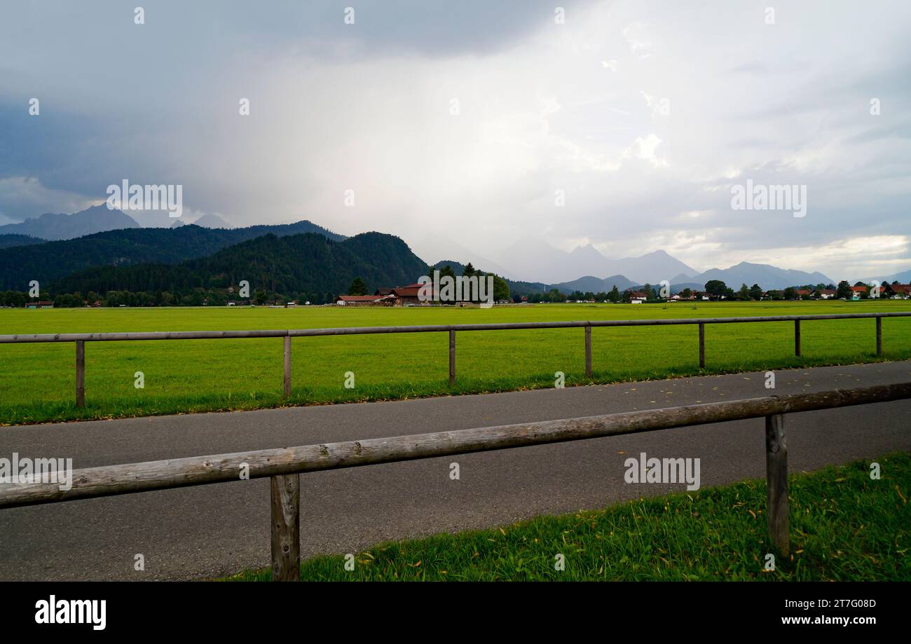 Des prairies alpines pittoresques et verdoyantes du village de Schwangau avec les Alpes bavaroises en arrière-plan dans la région d'Allgaeu en Bavière, en Allemagne Banque D'Images