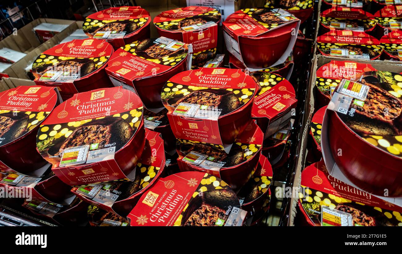 Affichage empilé de puddings de Noël affinés de 6 mois dans un emballage rouge festif sur une étagère de supermarché, prêt pour la saison des fêtes. Banque D'Images