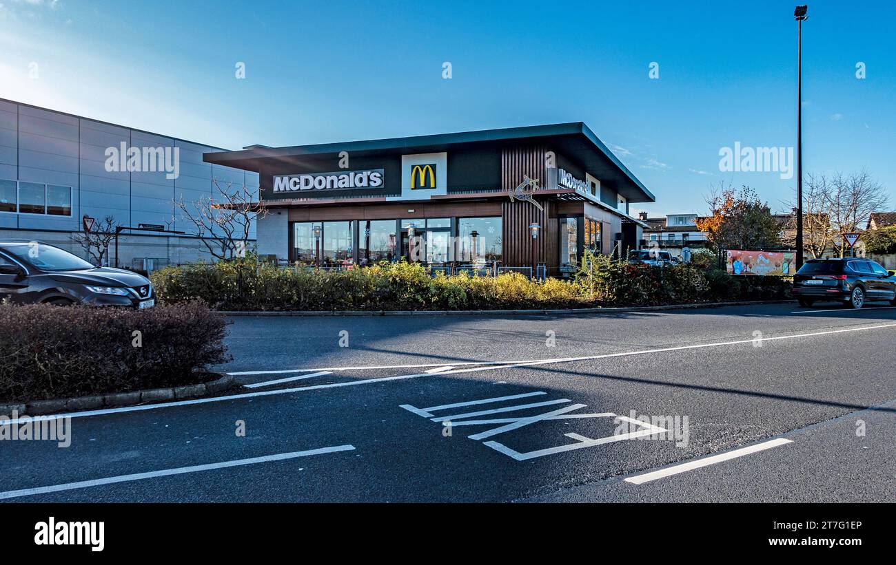Vue extérieure d'un restaurant de restauration rapide McDonald's avec ciel bleu clair et accès au parking. Banque D'Images