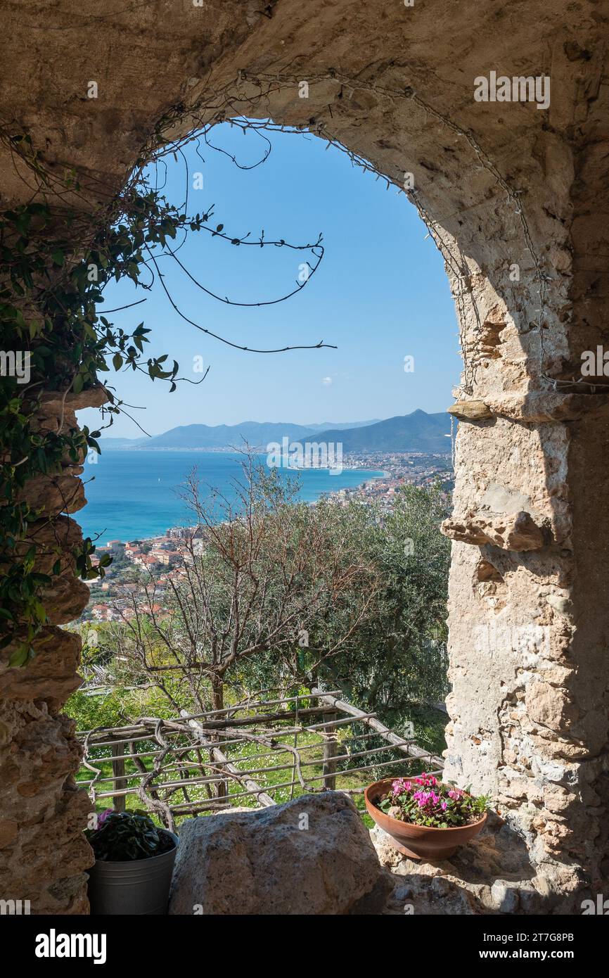 Vue sur la Riviera des palmiers depuis une arche en pierre du porche Roccaro dans le village médiéval de Borgio Verezzi, Savone, Ligurie, Italie Banque D'Images