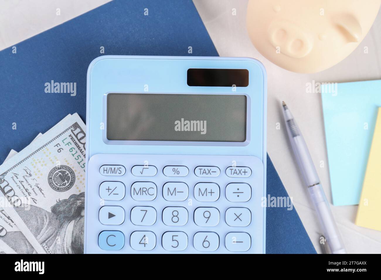 Calculatrice, billet de banque dollar, cahier, stylo et tirelire sur table gris clair, pose à plat. Concept de retraite Banque D'Images