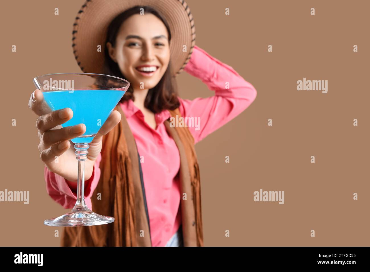 Femme barman habillé comme cow-girl avec cocktail sur fond beige, closeup Banque D'Images