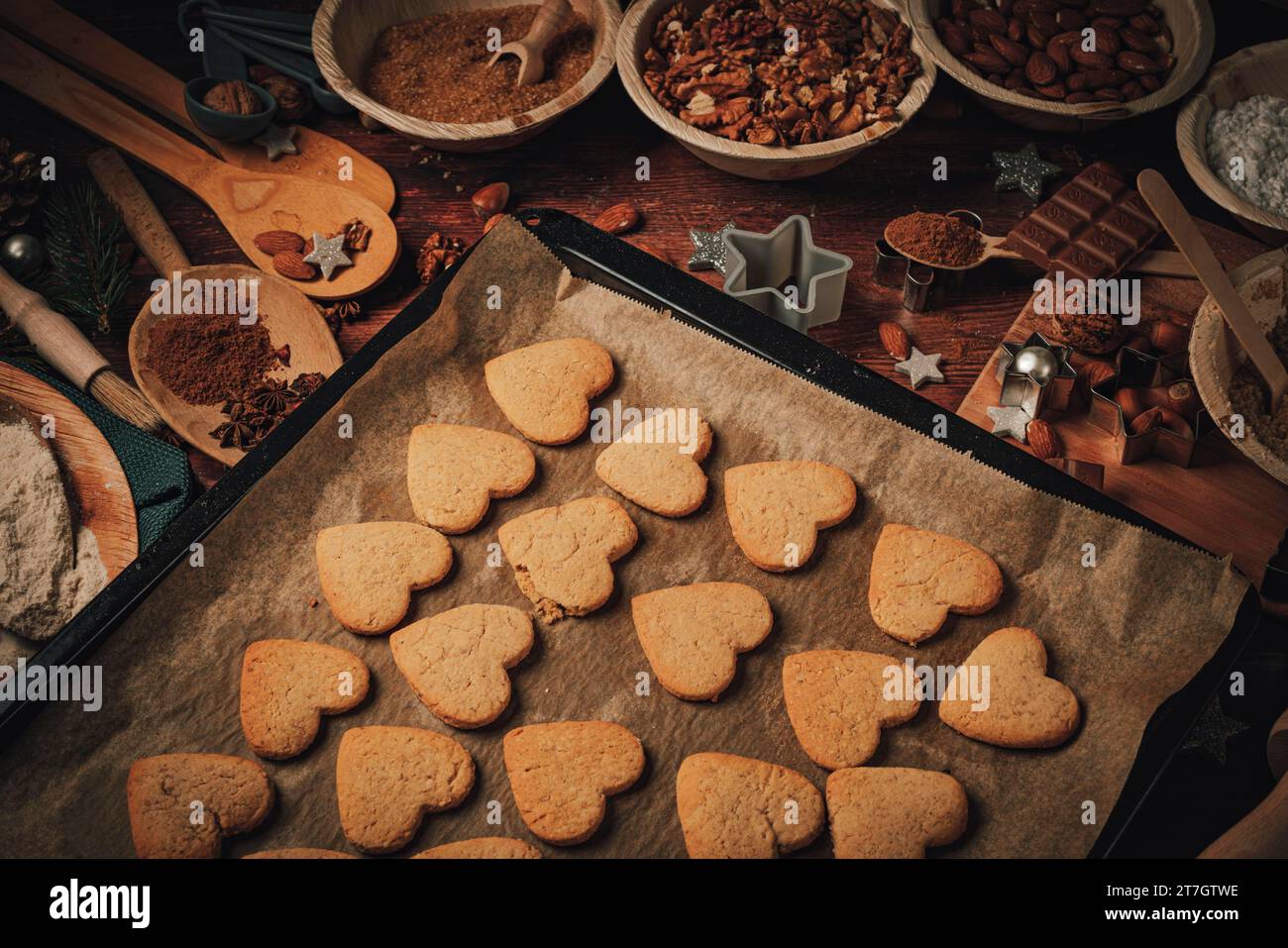 Biscuits en forme de coeur cuits sur une plaque de cuisson, ingrédients de cuisson, farine, sucre, amandes, noix, chocolat, cannelle, emporte-pièces Banque D'Images