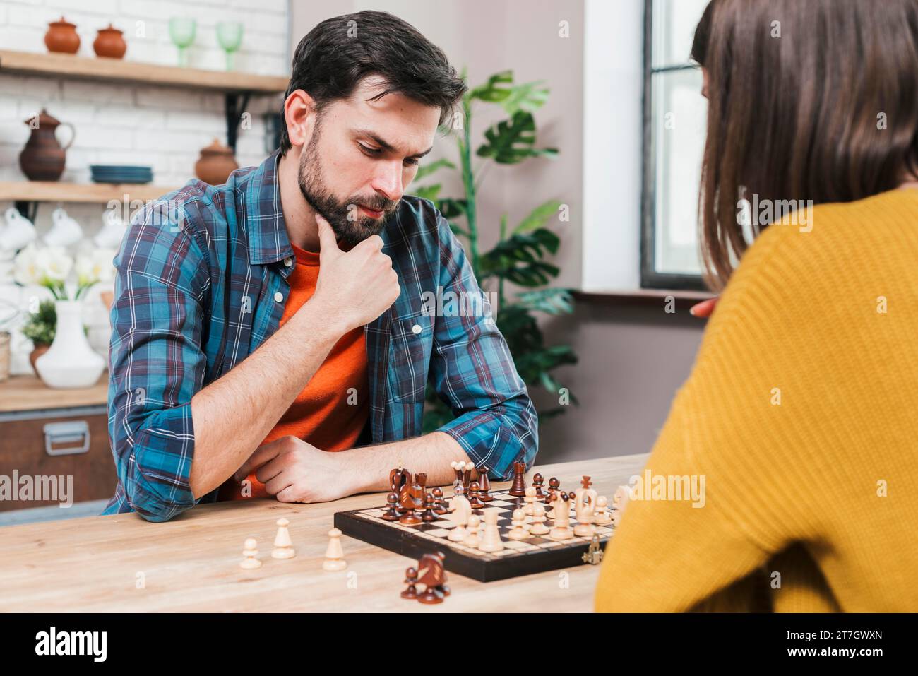 Contemplé jeune homme jouant un jeu d'échecs avec sa femme à la maison Banque D'Images