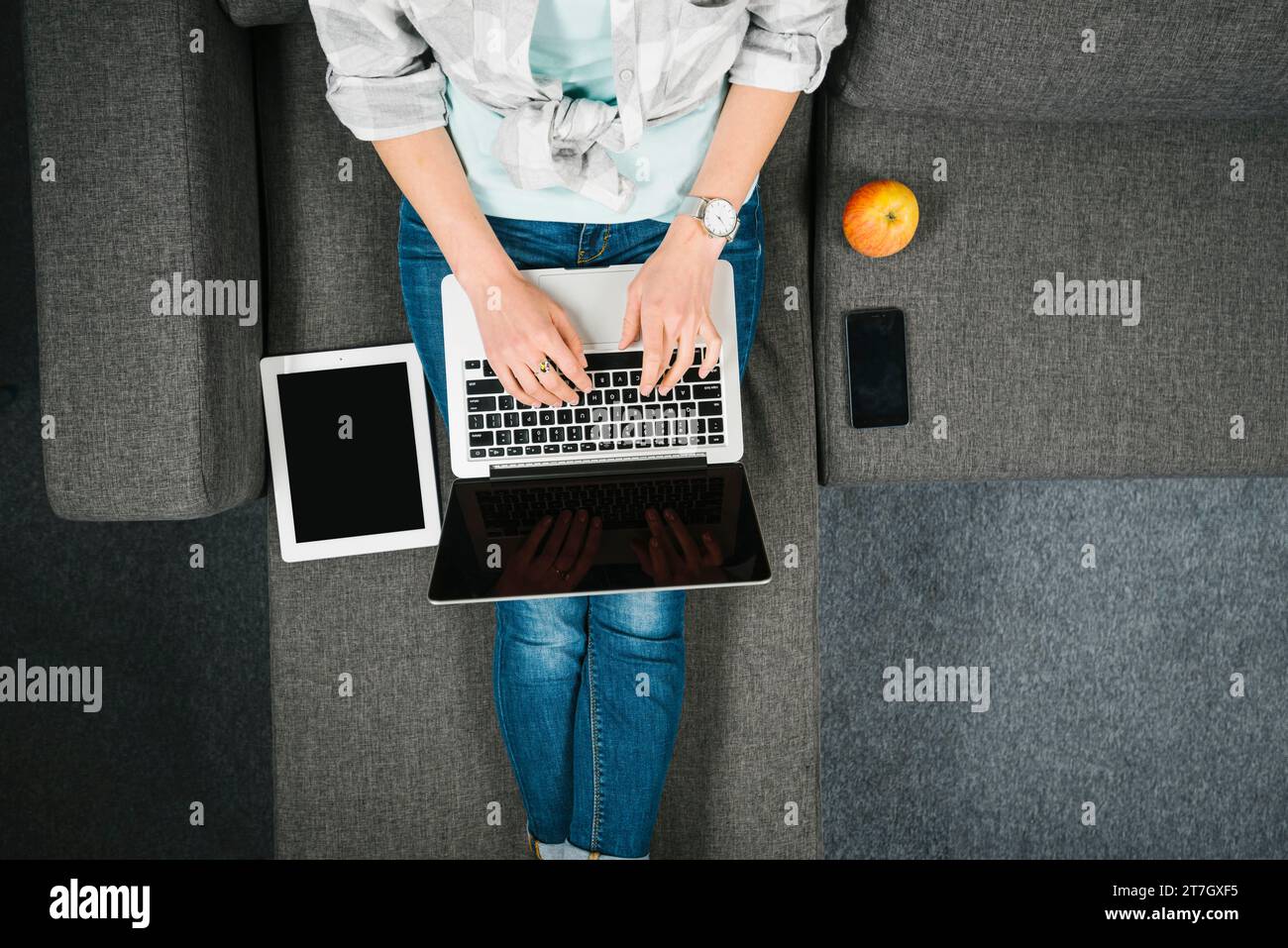 De femme naviguant sur le canapé d'ordinateur portable Banque D'Images