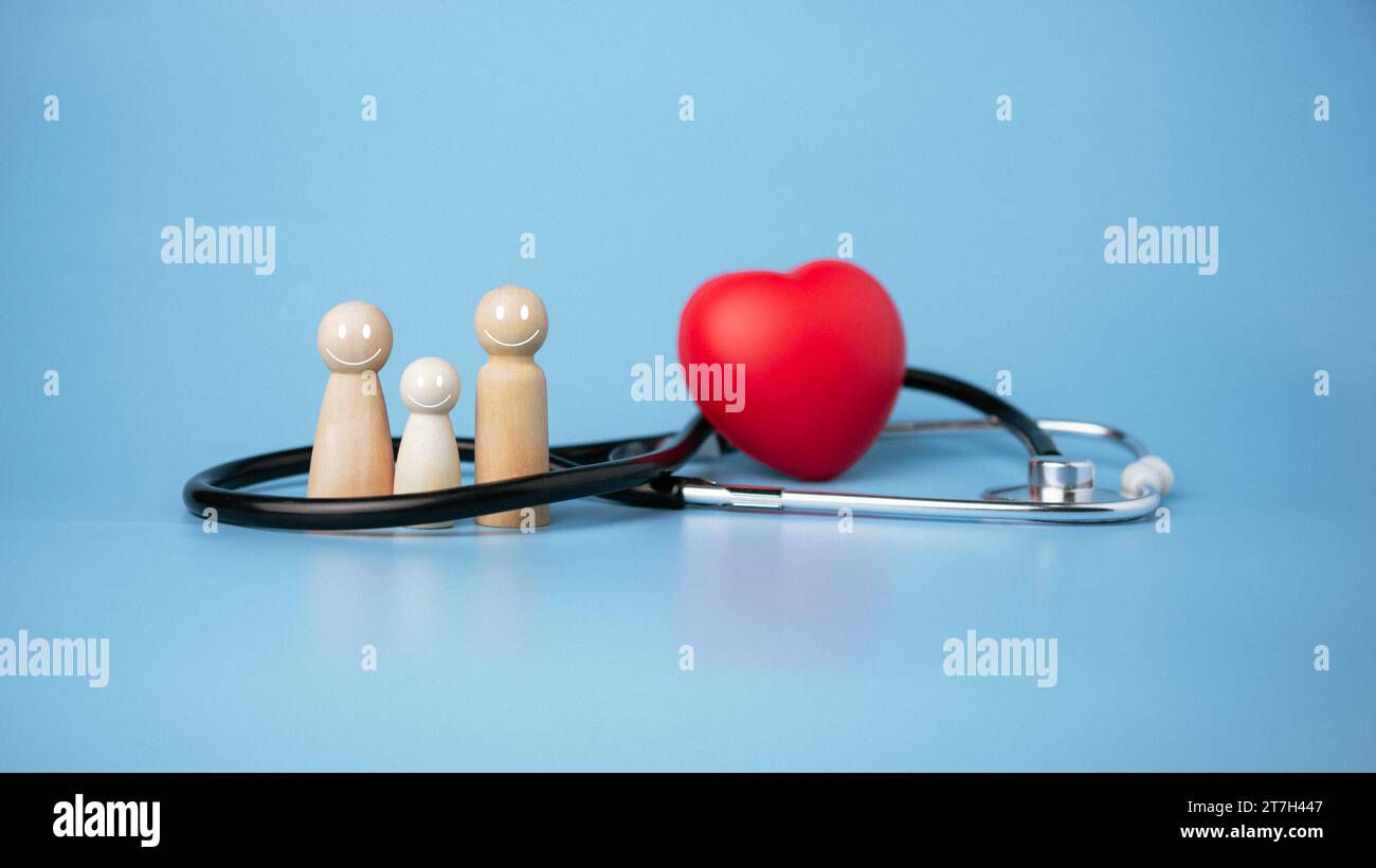 Concept d'assurance maladie et de bien-être médical, poupée en bois et coeur rouge avec stéthoscope sur fond bleu, assurance maladie et accès à la santéc Banque D'Images