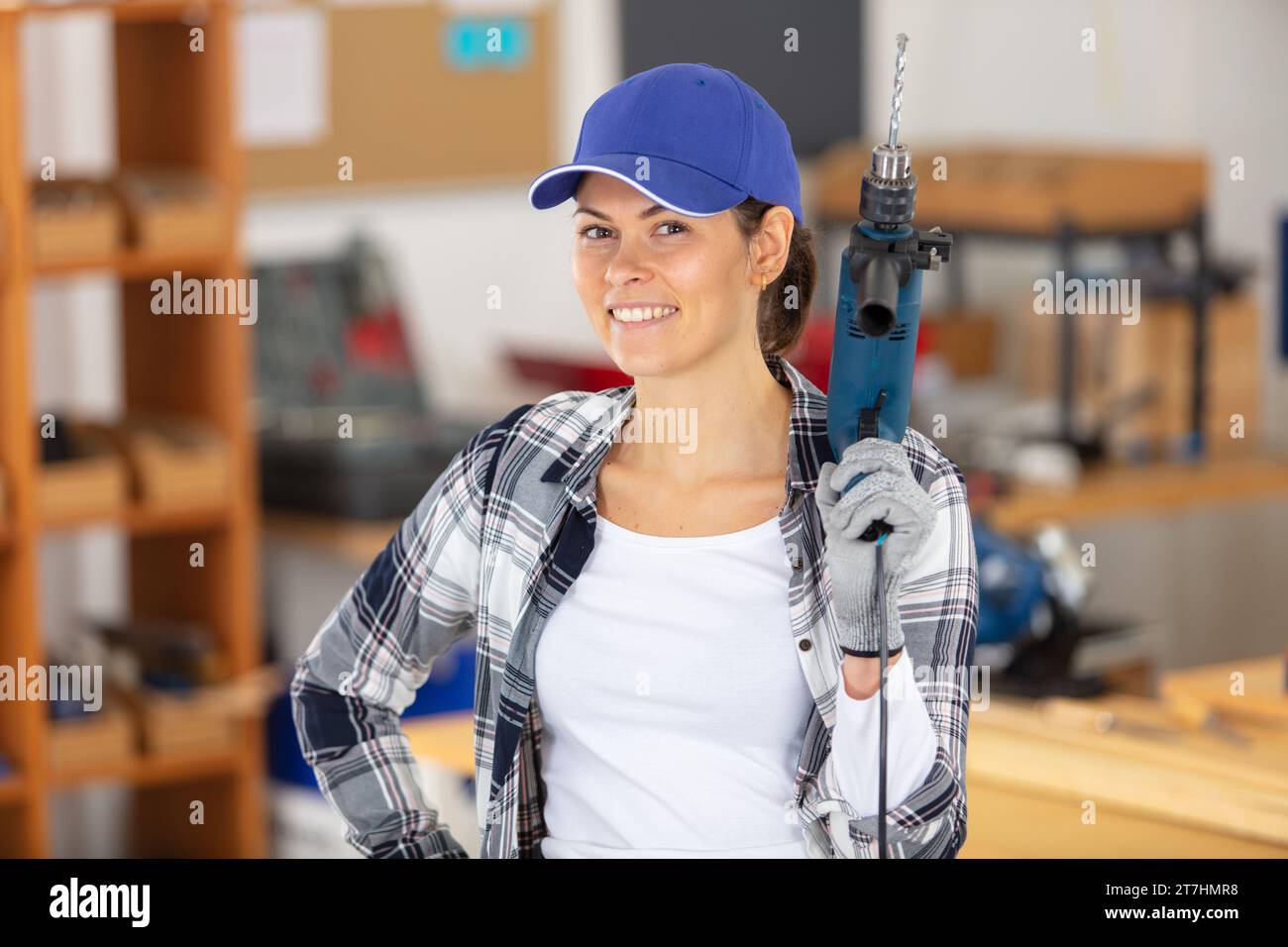 femme souriante dans l'atelier tient un outil électrique Banque D'Images