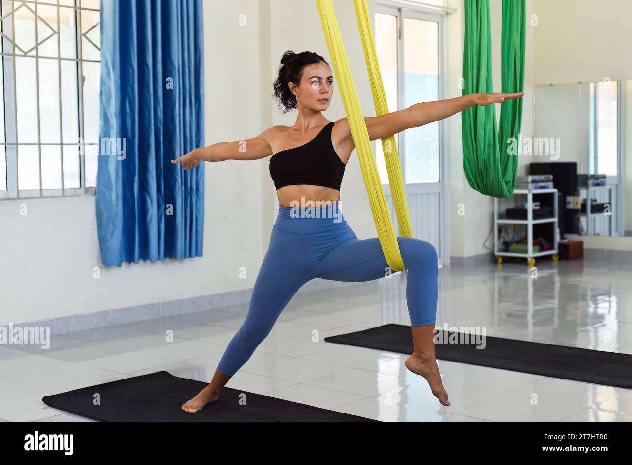 Jeune femme faisant la pose aérienne ou de yoga de mouche guerrier Banque D'Images