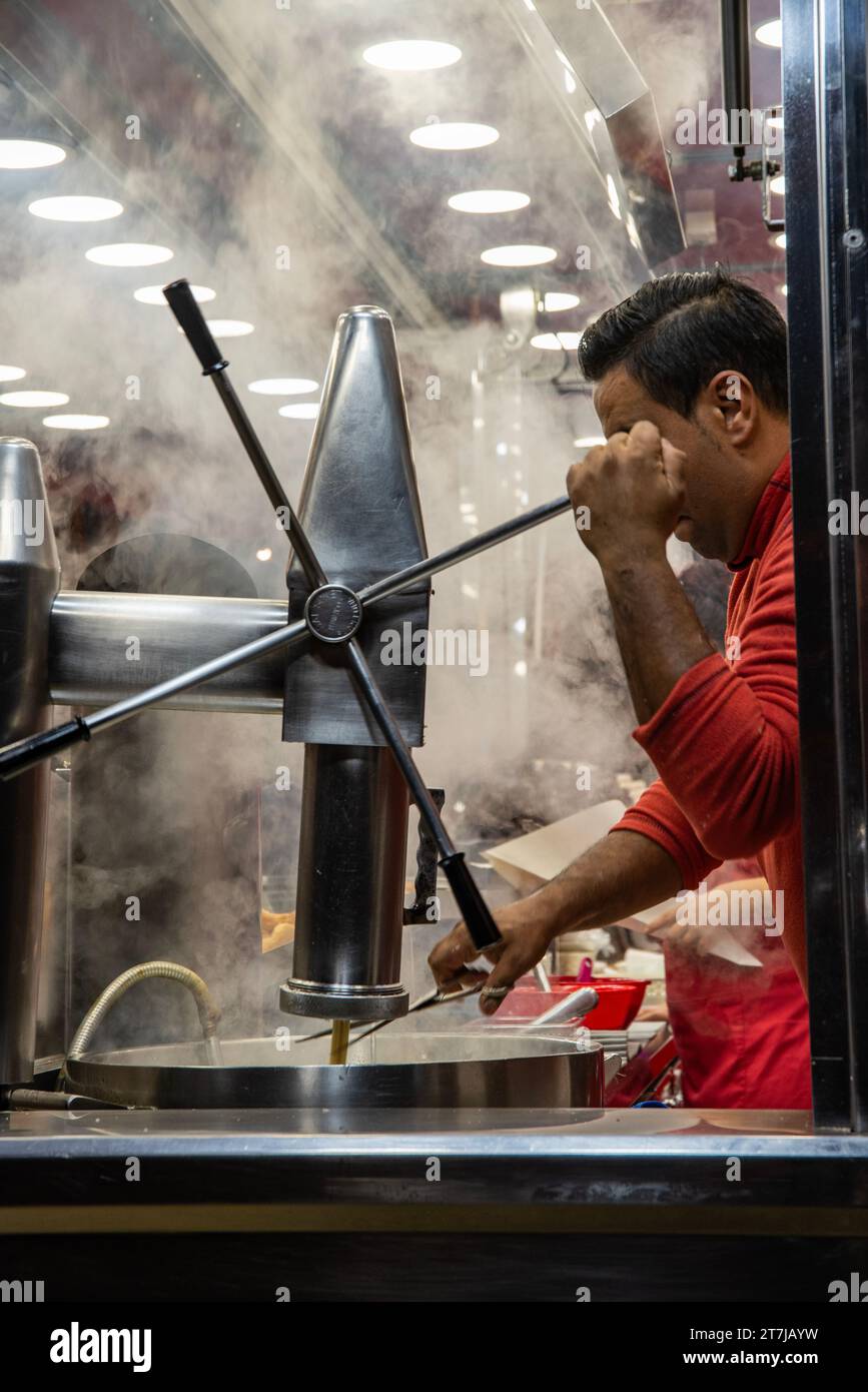 Capturez l'essence de l'art culinaire de rue de Barcelone : un artisan de churro qualifié enveloppé dans l'arôme de pâte fraîchement frite, créant un te Banque D'Images