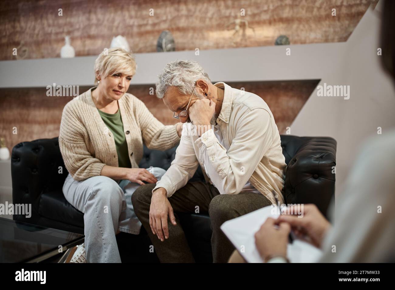 femme d'âge moyen attentionné calmant le mari contrarié pendant une séance de thérapie familiale avec psychologue Banque D'Images