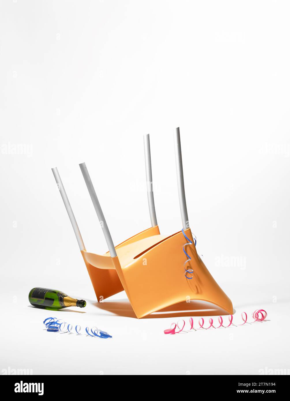 Après une célébration agitée ; chaise retournée, bouteille de champagne jetée, serpentins. Représentation de natures mortes photographiée en studio. Banque D'Images