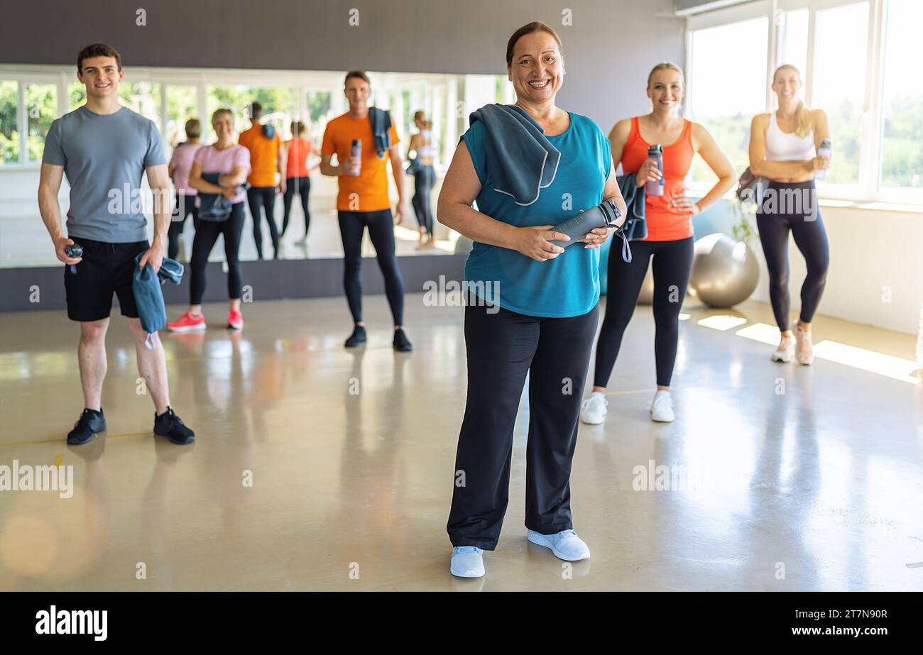 Groupe diversifié de sportifs avec équipement de fitness dans une salle de gym lumineuse, souriante et prête à s'entraîner. Image conceptuelle du travail d'équipe Banque D'Images