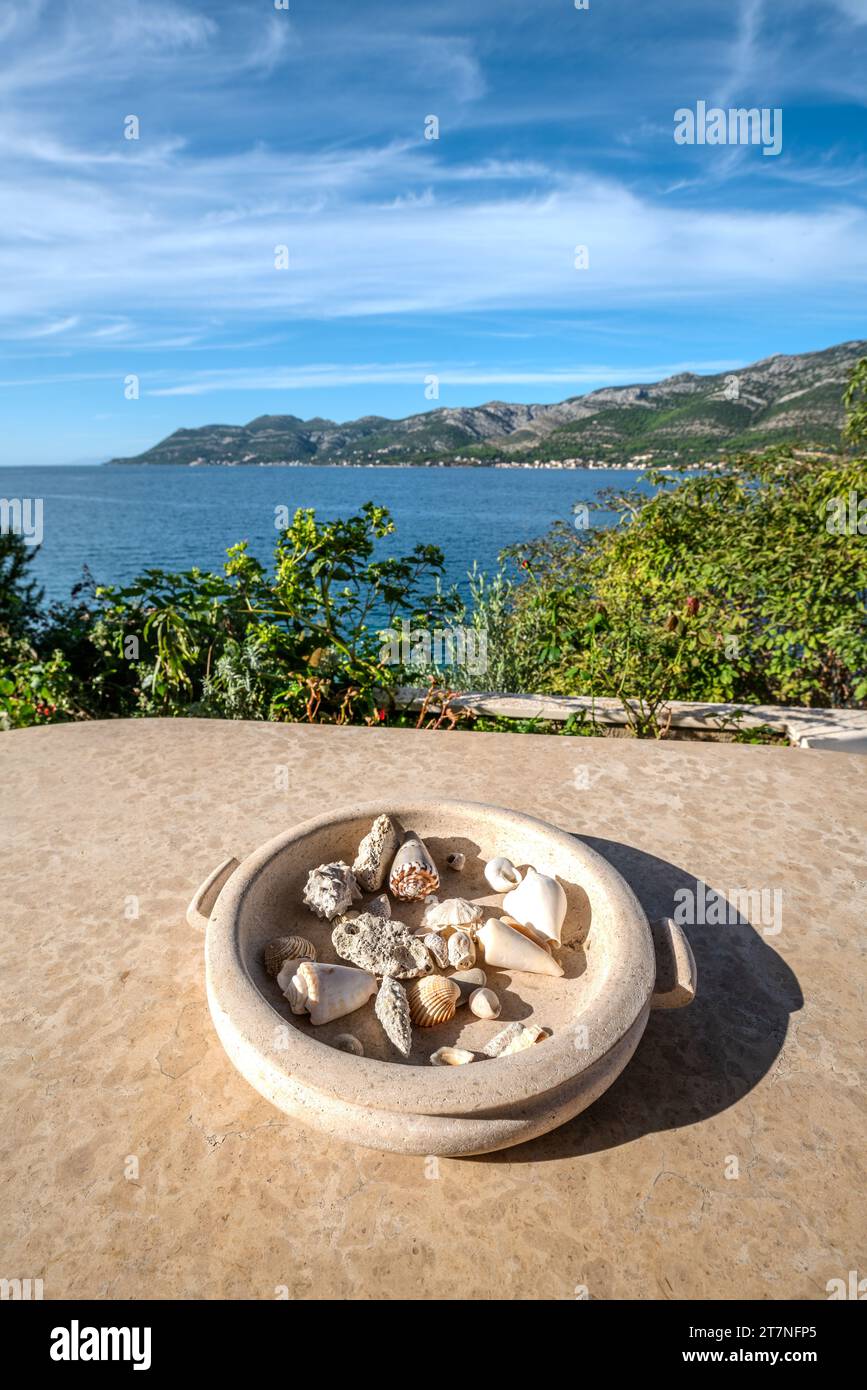 Plateau décoratif en pierre avec coquillages sur une table de terrasse donnant sur la mer Banque D'Images