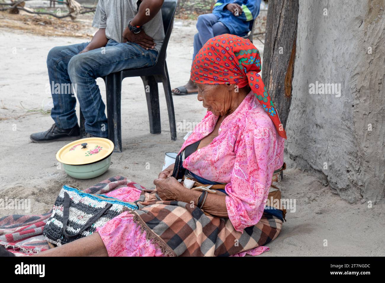 vieille femme de village africain avec famille situé sur le sol en face de la maison Banque D'Images