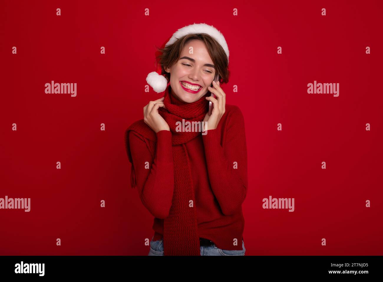 Belle dame excitée dans le chapeau de Santa rouge parle au téléphone avec bien-aimé ou des amis. Joyeux noël. Bonne année. Vacances et célébration Banque D'Images