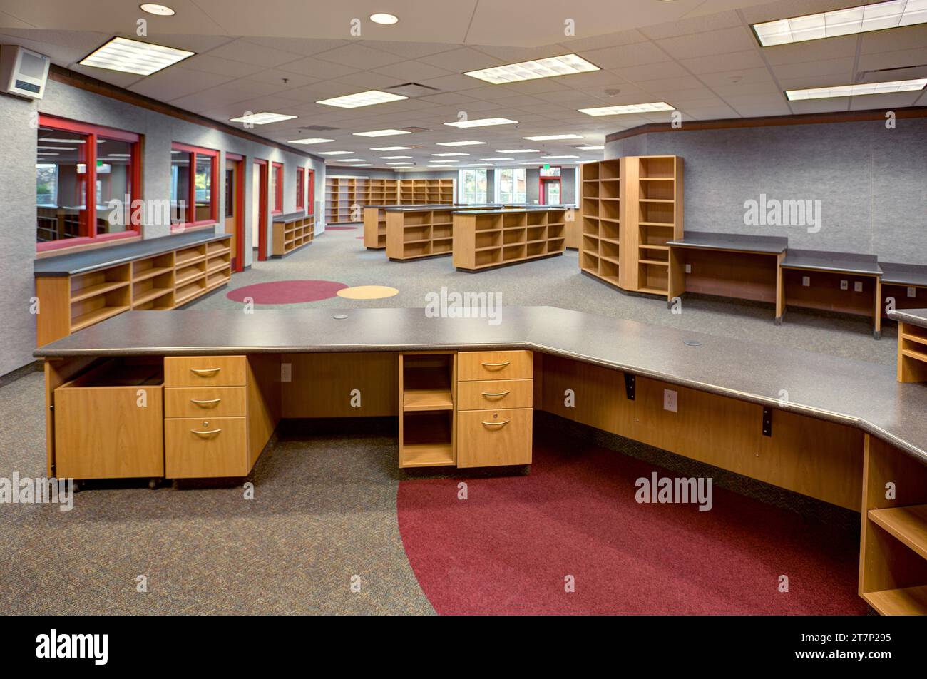 Le centre des médias et la bibliothèque dans un lycée public moderne avec bureau de checkout, étagères vides et piles. Banque D'Images