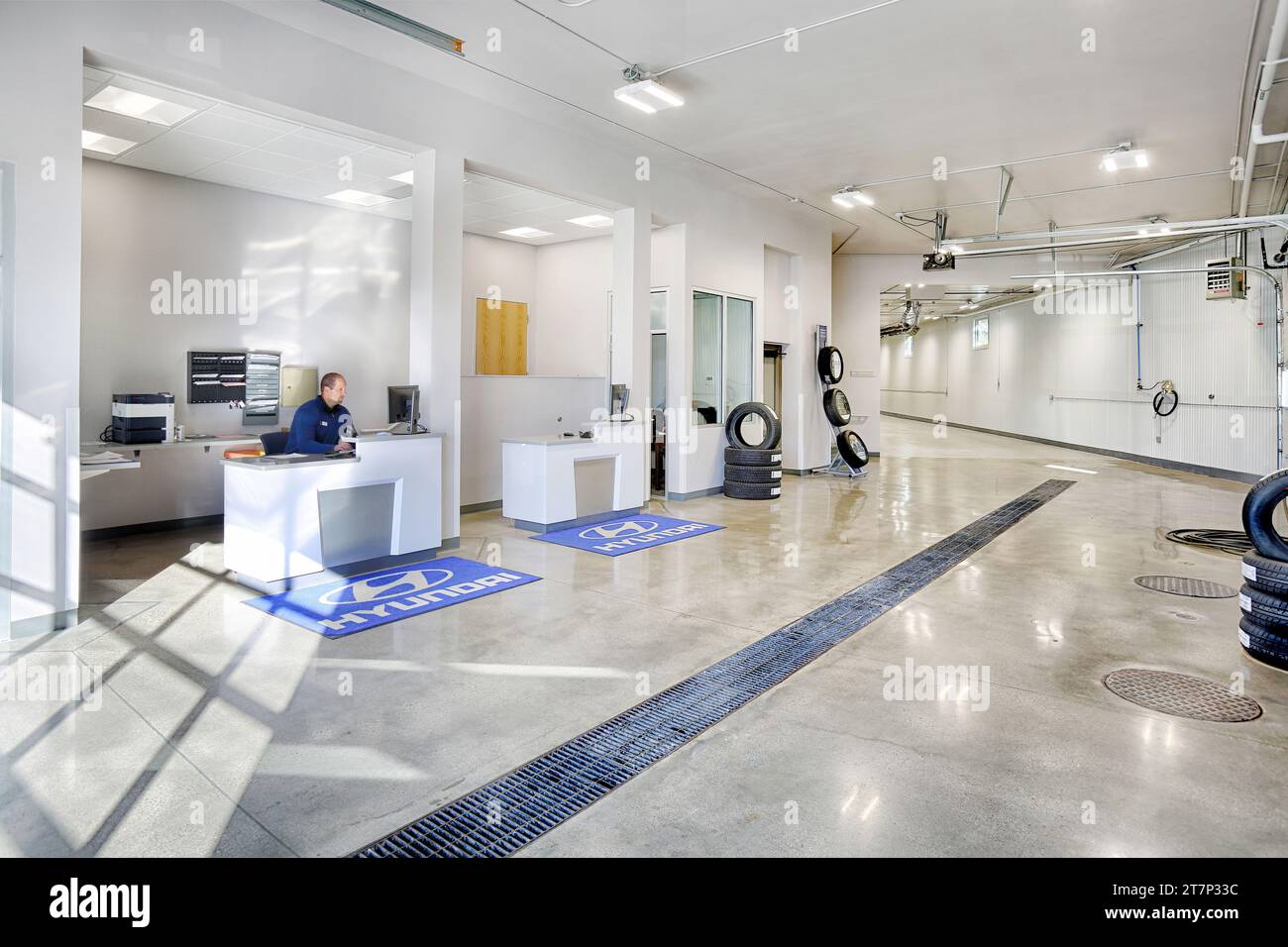 Un technicien de service assis à la réception dans la zone de réception d'un atelier de réparation automobile moderne, Banque D'Images