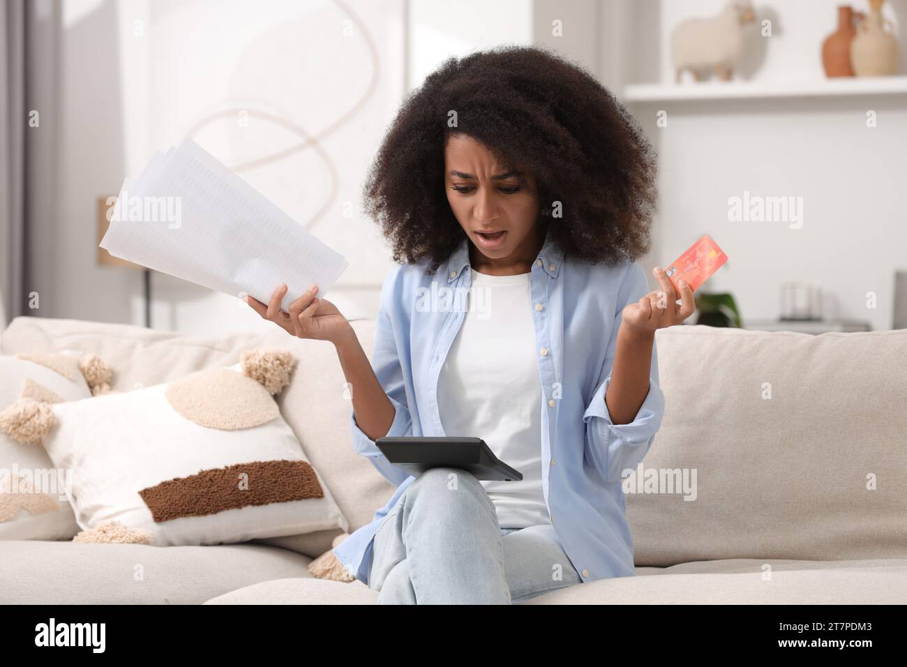 Femme choquée avec calculatrice et budget de planification de carte de crédit à la maison. Problème de dette Banque D'Images