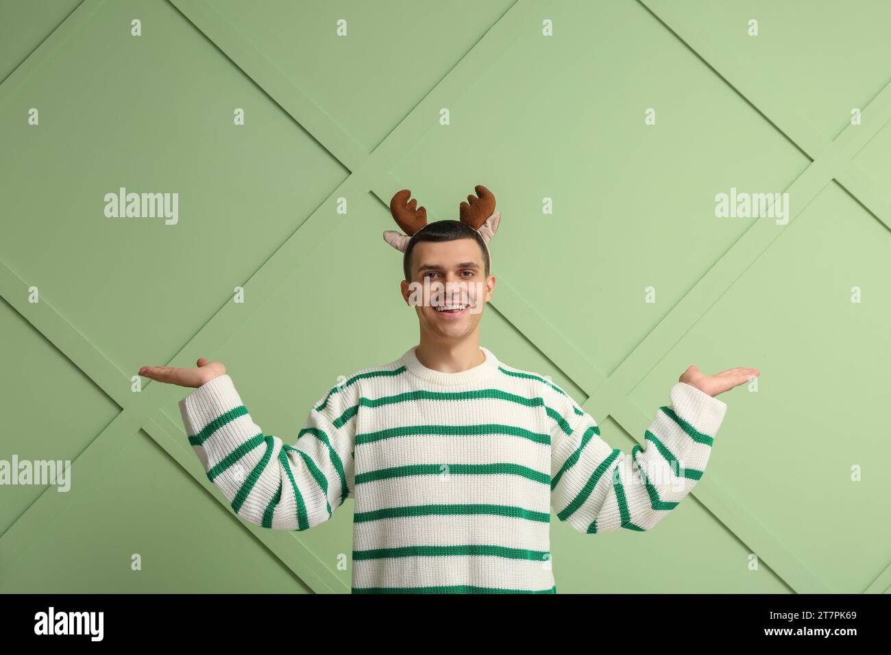 Heureux jeune homme en cornes de renne sur fond vert Banque D'Images