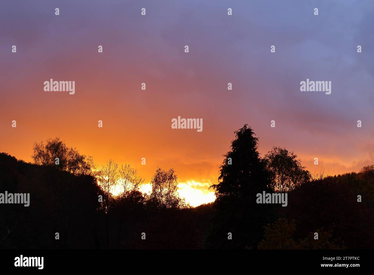 Coucher de soleil avec nuages sombres dramatiques, soleil brillant à travers un trou dans les nuages, ciel rouge, ciel brûlant, silhouette, Rothaargebirge, Rhénanie du Nord-Westphalie Banque D'Images