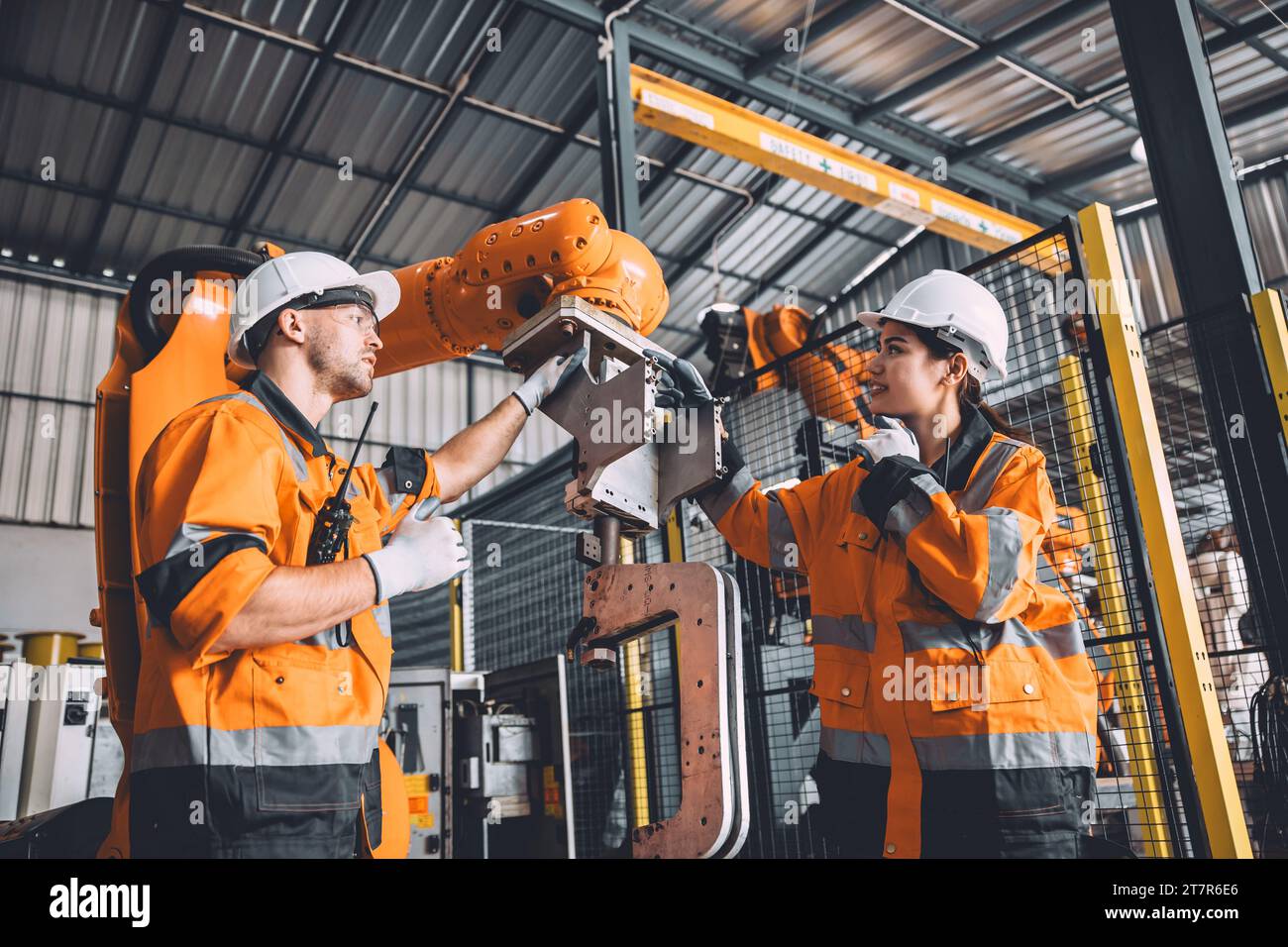 L'équipe d'ingénieurs assure le service de soudage des robots travaillant dans l'usine d'automatisation. Les personnes travaillant en costume de sécurité travaillent robotique ARM logiciel de programmation ou de remplacement par Banque D'Images
