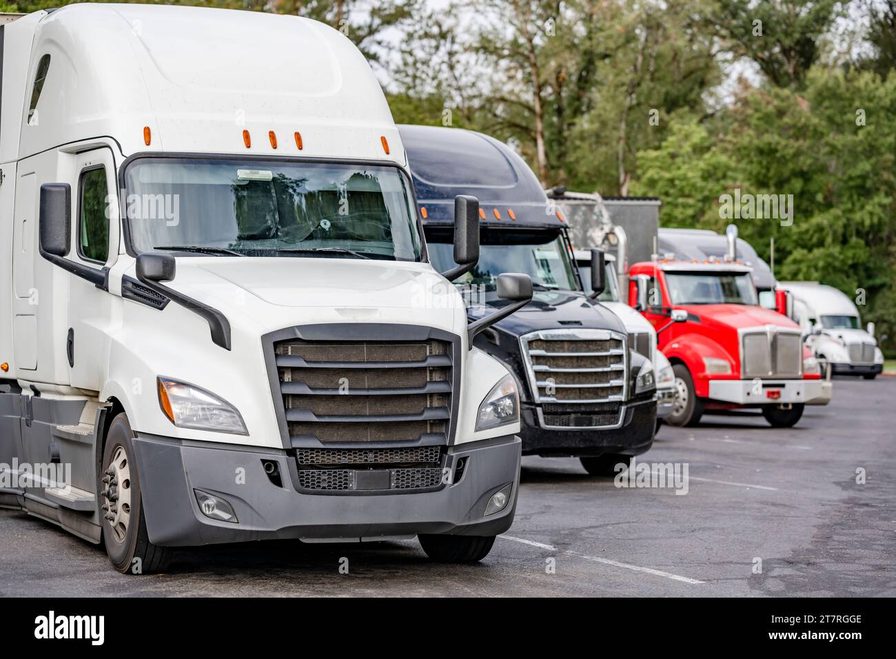 Transporteurs de longue haleine industriels différents tracteurs semi-camions big rig avec semi-remorques chargées debout en rangée sur le parking de l'aire de repos de la route Banque D'Images