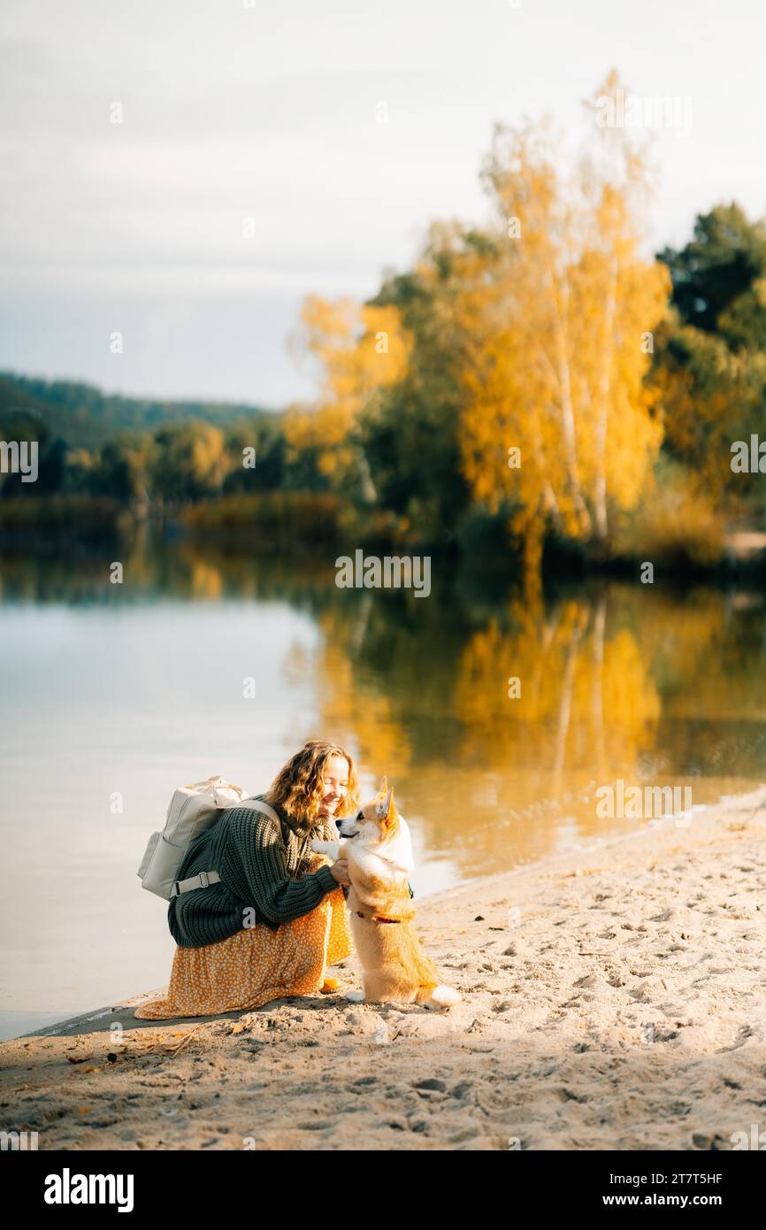 Jeune femme jouant avec le chien corgi sur la plage près du lac Banque D'Images
