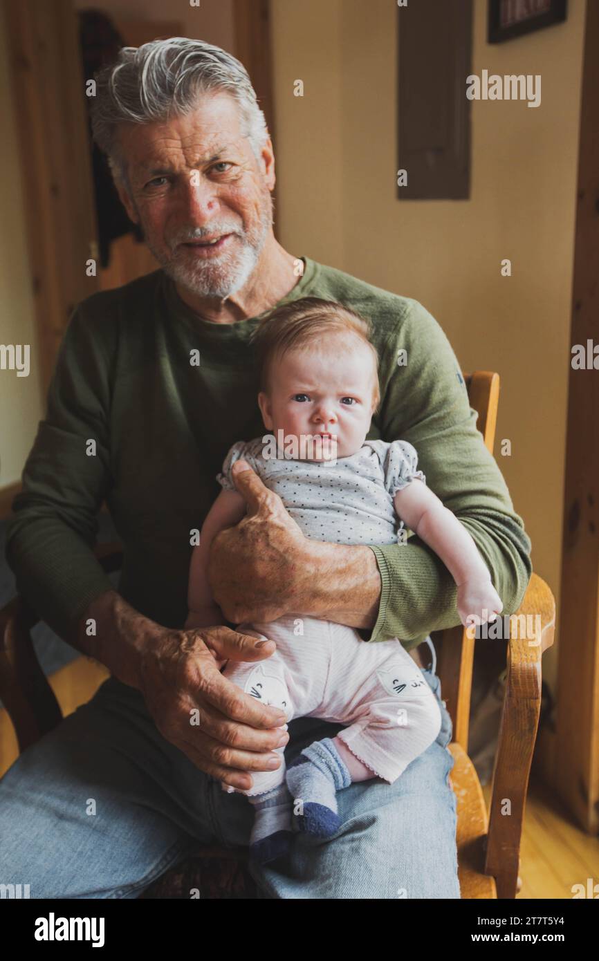 Grand-père souriant tenant la petite-fille Serious Baby Banque D'Images