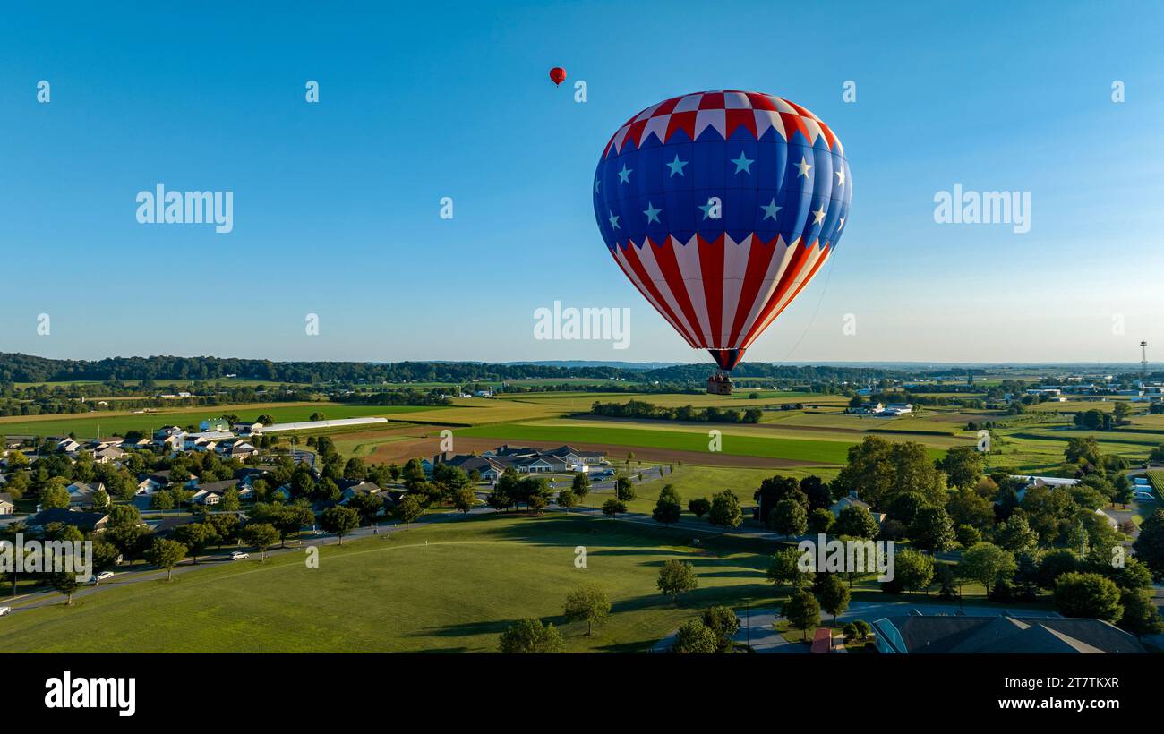 Une vue aérienne sur une étoile et des rayures, montgolfière flottant au-dessus d'une communauté de campagne, par une belle journée d'été Banque D'Images