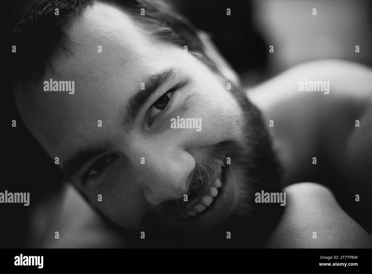 Portrait, sourire et homme à la maison, monochrome et détente dans le salon de l'appartement ou de la maison. Visage heureux de la jeune personne sur noir et blanc, sombre et Banque D'Images