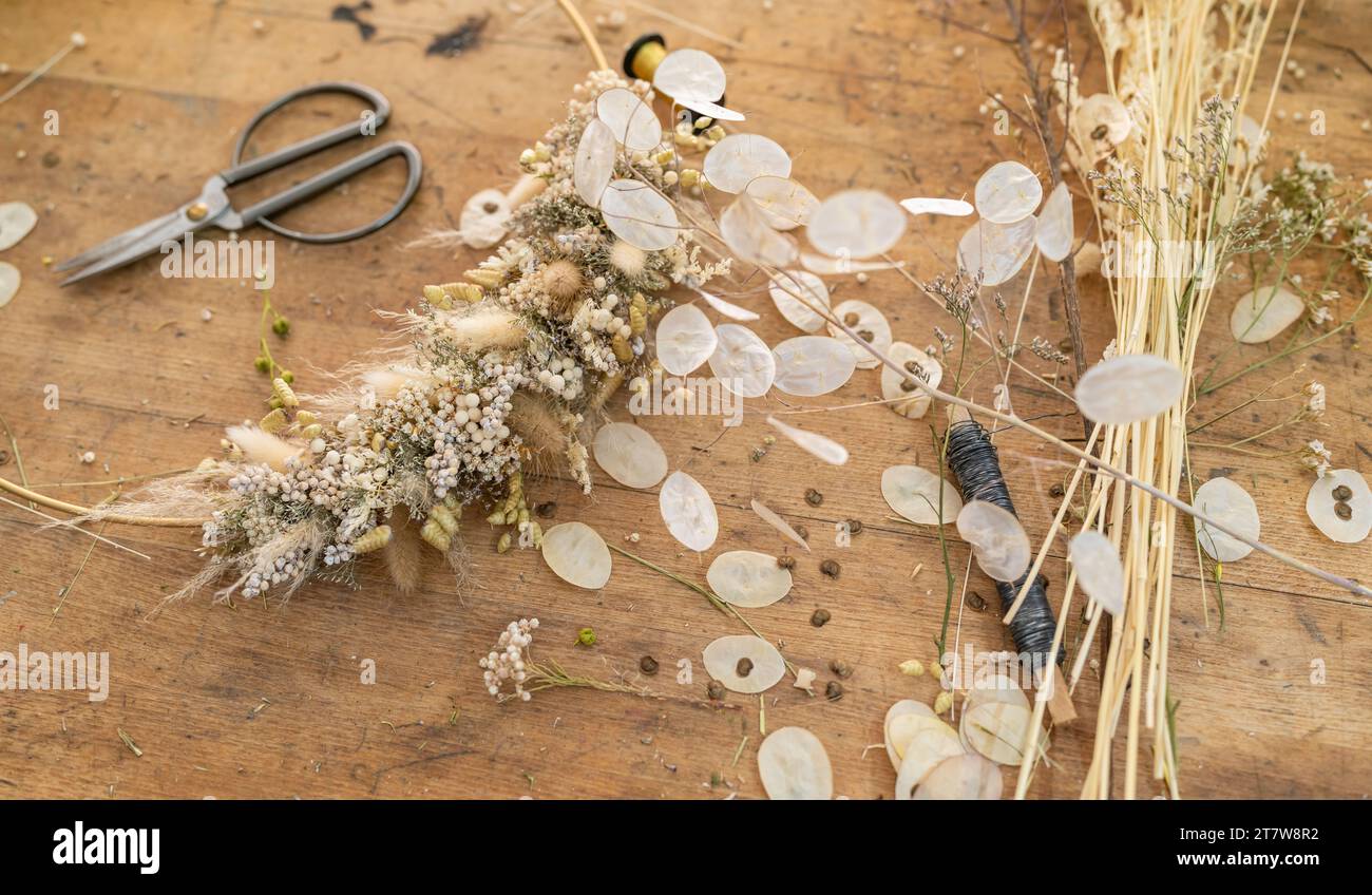 Arrangement floral séché sur une table en bois avec des ciseaux et des paquets de blé et de fleurs Banque D'Images