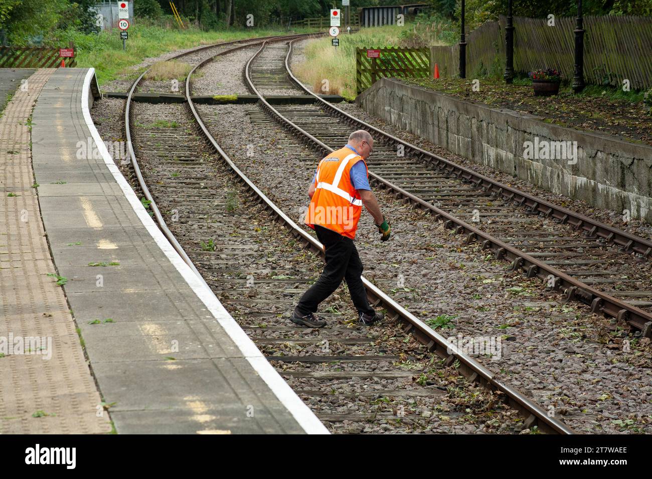 Entretien ferroviaire en cours : un travailleur ferroviaire revêtu de haute visibilité orange effectue avec diligence l'entretien de la voie, assurant le bon fonctionnement du rail Banque D'Images