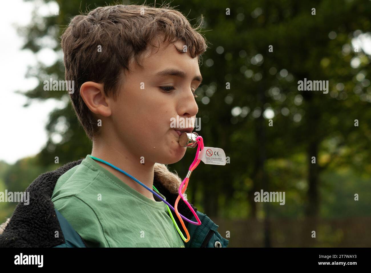 Sifflet in the Wilderness : un garçon de 12 ans plein d'esprit tire joyeusement un sifflet sur fond d'arbres verdoyants Banque D'Images