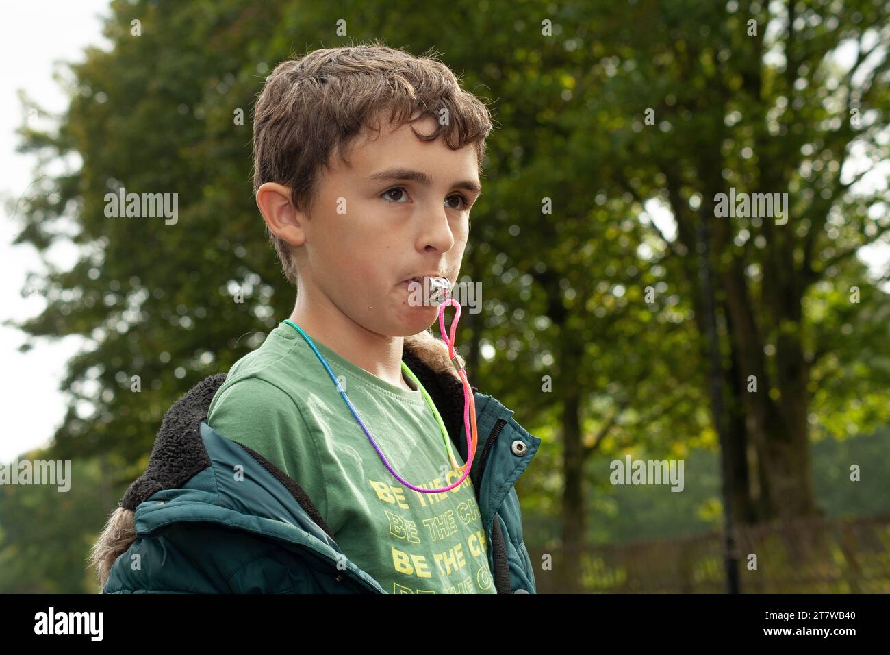 Sifflet in the Wilderness : un garçon de 12 ans plein d'esprit tire joyeusement un sifflet sur fond d'arbres verdoyants Banque D'Images