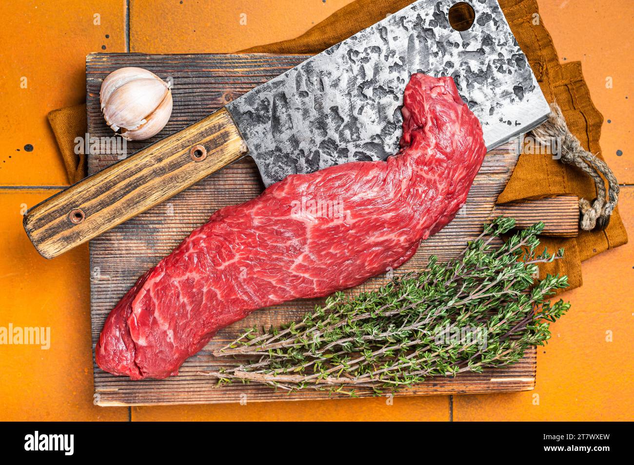 Steak de viande de bœuf à la machette fraîche brute ou tendre sur la planche à découper du boucher. Arrière-plan orange. Vue de dessus. Banque D'Images