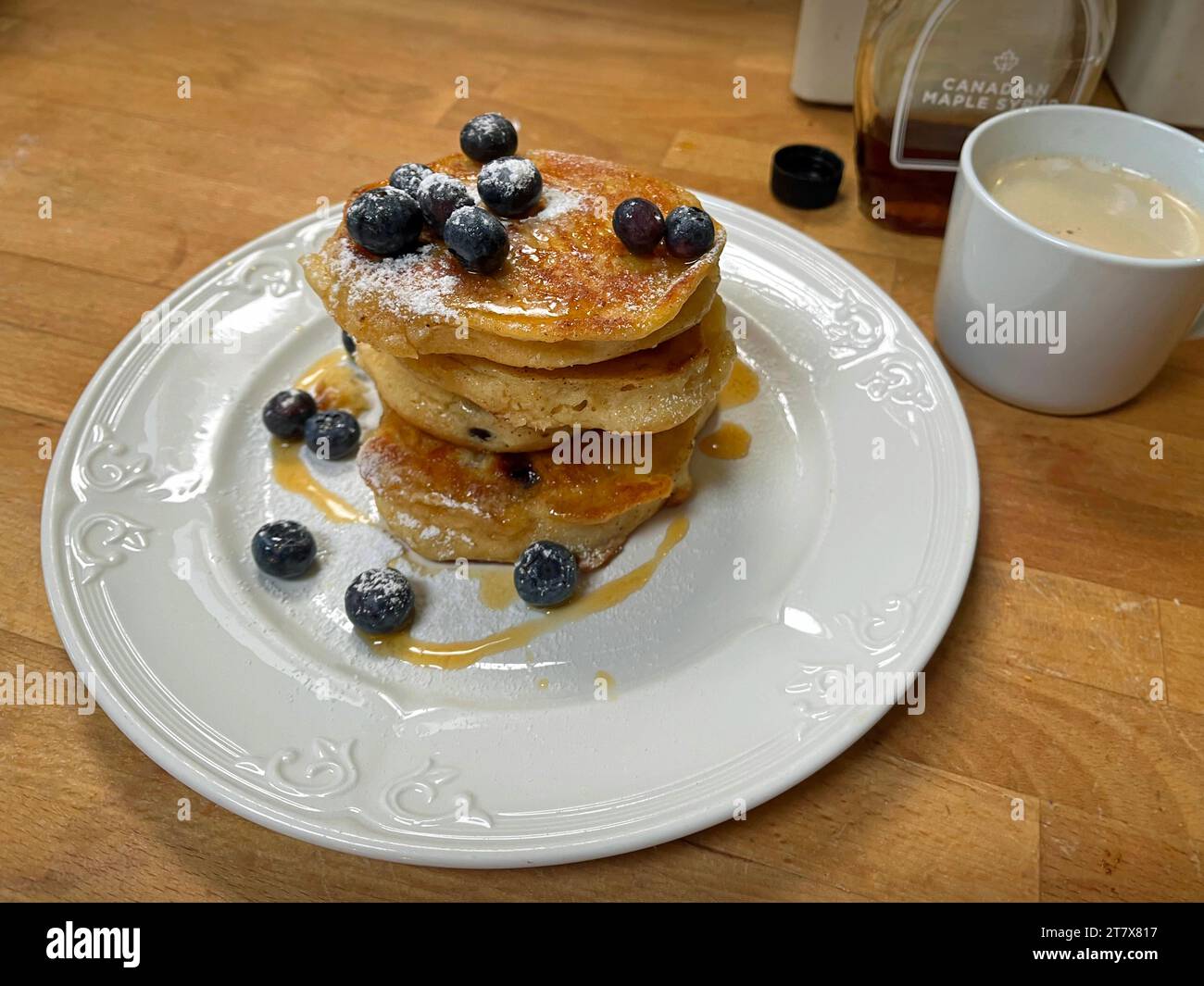 Une pile de crêpes aux myrtilles fraîchement préparées avec du sirop d'érable et du café. Banque D'Images