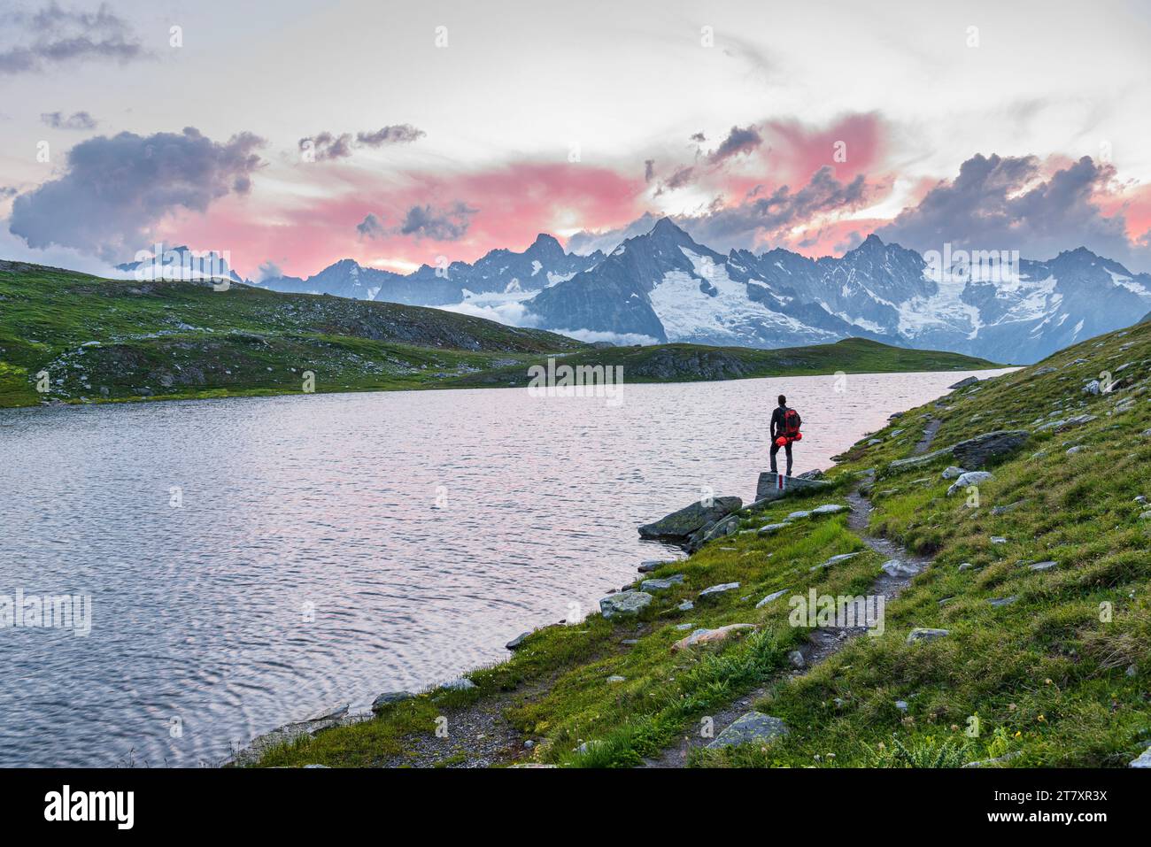 Randonneur se dresse près de la rive du lac de Fenetre admirant le coucher de soleil sur le massif du Mont blanc, vallée du Ferret Banque D'Images
