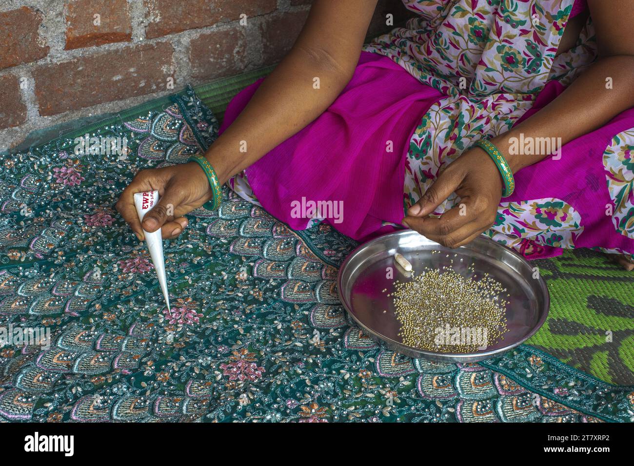 Femme adivasi collant des perles sur un sari dans un village du district de Narmada, Gujarat, Inde, Asie Banque D'Images