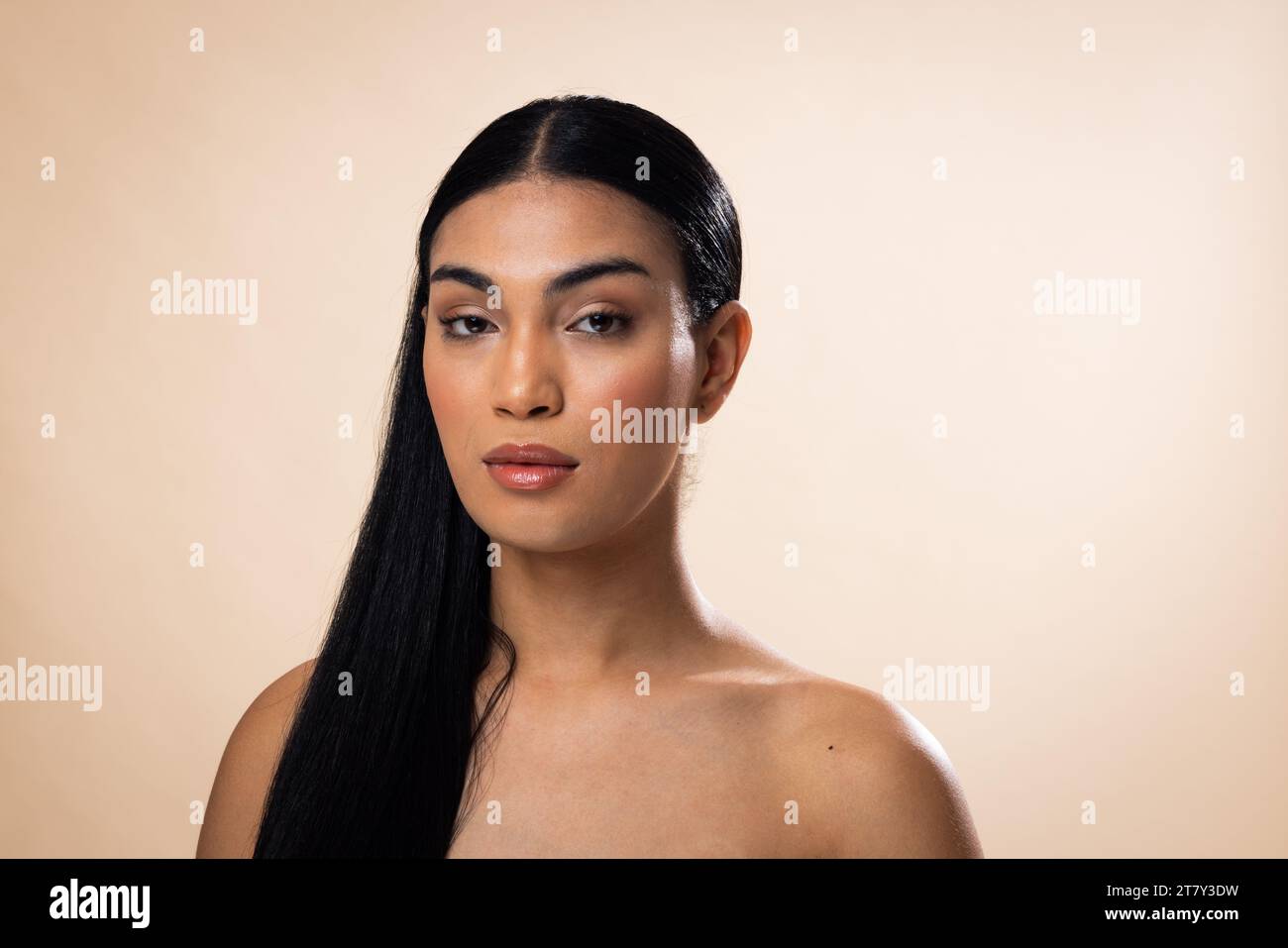 Portrait de femme biracial avec les cheveux foncés et maquillage naturel sur fond brun Banque D'Images