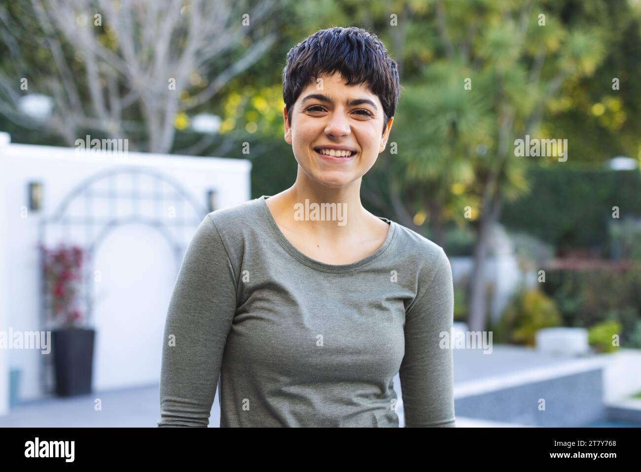 Portrait de femme biracial heureuse avec les cheveux foncés courts debout sur la terrasse de jardin souriant Banque D'Images
