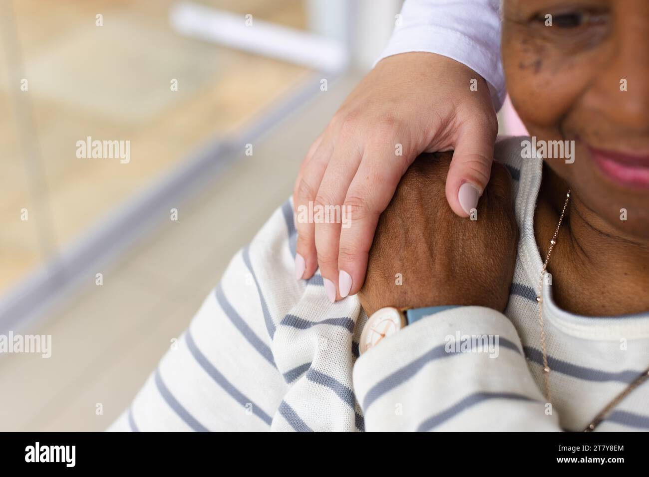 Main d'infirmière caucasienne sur l'épaule d'une femme afro-américaine senior Banque D'Images
